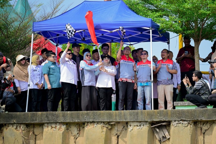 Bupati Hj Kasmarni saat mengibarkan bendera melepas pacu sampan sebagai tanda dimulainya perlombaan.